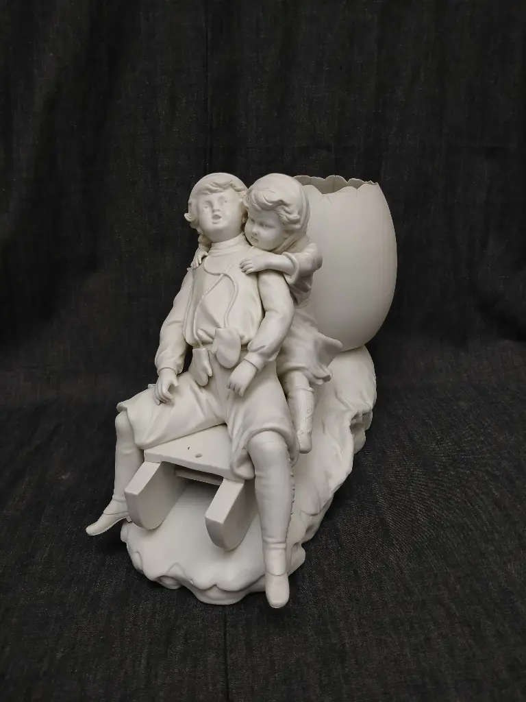 Groupe en biscuit de porcelaine représentant deux enfants sur une luge et un œuf 