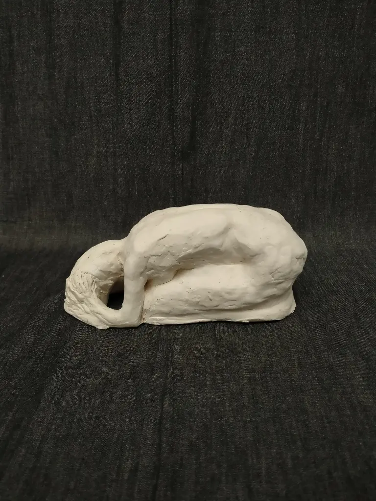 Sculpture en terre cuite blanche représentant une femme recroquevillée sur elle-même 